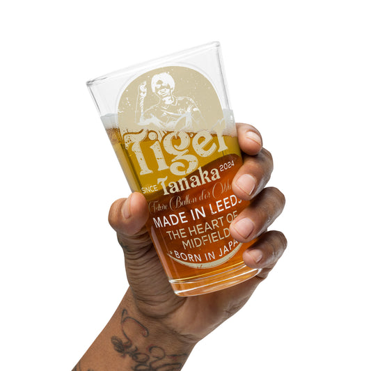Hand holding a glass of beer with 'Tiger Tanaka' branding on a white background